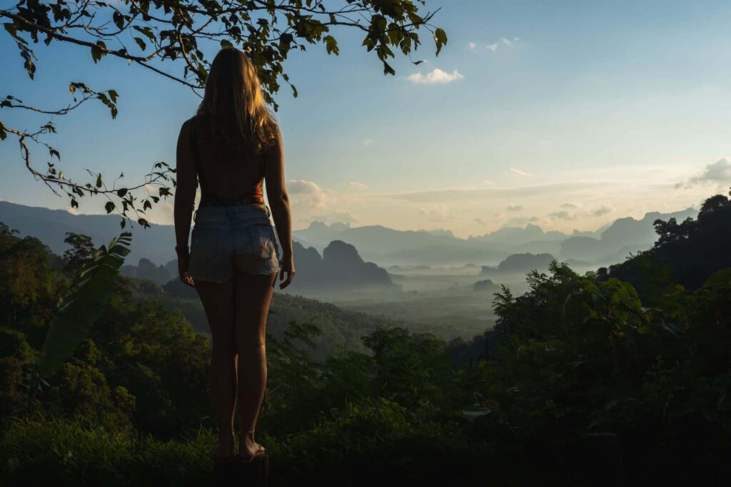 Femme contemplant un paysage brumeux de montagnes karstiques à l'aube, habitat naturel de la riche faune de Khao Sok